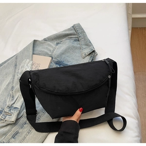 Detail of black nylon crescent bag with wide strap and zip pocket on white backdrop