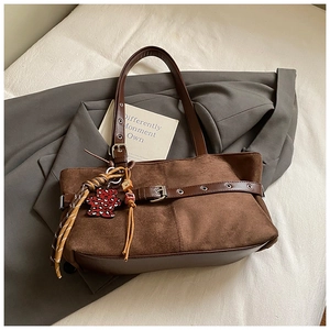 Close-up of brown suede tote with metal buckle detail and leopard bear charm
