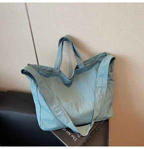 Détail du grand sac cabas bleu sarcelle en nylon froissé posé sur un banc en cuir