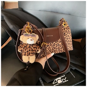 Détail du sac vintage en cuir marron avec panneau léopard et breloque ours en peluche