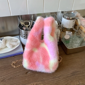 Detail of pink and white plush bucket bag with soft texture and golden metal chain strap