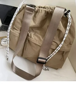 Detail of adjustable nylon strap and dual front zipper pockets on khaki tote bag