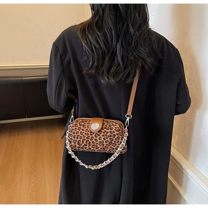 Détail du sac léopard avec chaîne argentée et bandoulière en cuir sur un manteau noir