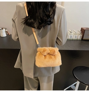 Détail d'un sac bandoulière en fausse fourrure caramel porté pour montrer la taille