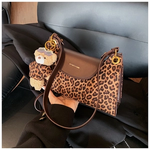 Détail d'un sac vintage en cuir marron avec motifs léopard et un charmant ours en peluche