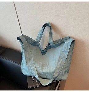Gros plan du sac fourre-tout en nylon bleu clair texturé sur un siège en cuir