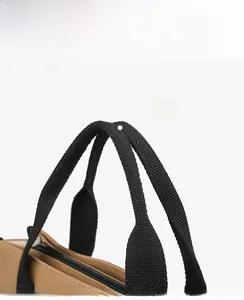 Close-up of brown canvas tote bag featuring durable black woven handles and zipper detail