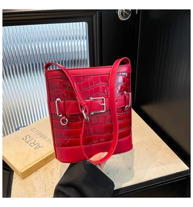 Détail macro du sac seau rouge à texture crocodile avec boucle et ferrures en argent