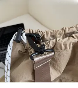 Detail of durable swivel hook and nylon strap on a khaki drawstring commuter tote bag
