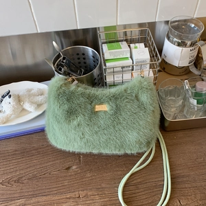 Détail du sac à main en fausse fourrure vert clair avec une plaque métallique dorée élégante