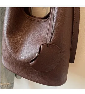 Close-up of deep brown litchi grain leather bucket bag with detailed stitching and texture