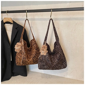 Detail view of large leopard print tote bags with cute plush bear charms hanging on hooks