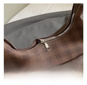 Detailed view of metal zipper and high-quality stitching on coffee checkered handbag