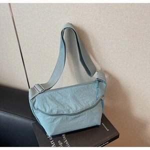 Close-up of light blue crescent nylon bag with adjustable strap on a book base