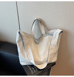 Gros plan sur la texture plissée et les détails du tissu de ce grand sac cabas beige