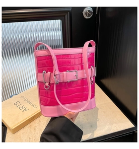 Détail du sac seau fuchsia à motif crocodile sur pierre avec des livres d'art