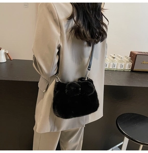 Détail du sac seau en peluche noire avec pompons doux et bandoulière en cuir