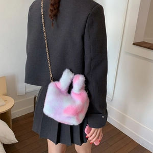 Detail of pink and white plush bucket bag with golden chain strap on a model