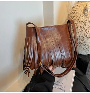 Detail einer braunen Vintage-Fransen-Beuteltasche aus Wildleder-Optik mit Quasten