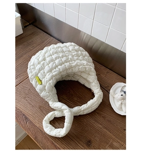 Detail einer weißen gesteppten Puffy-Tasche mit 3D-Textur und gelbem Fashion-Label