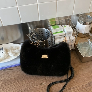 Détail du sac bandoulière en fausse fourrure noire avec logo doré et breloque ours blanc