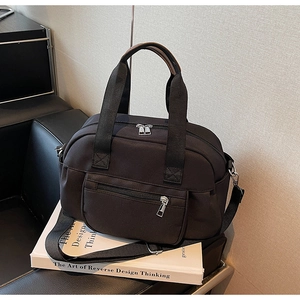 Detail of black canvas tote bag with brown leather handles on a black leather sofa