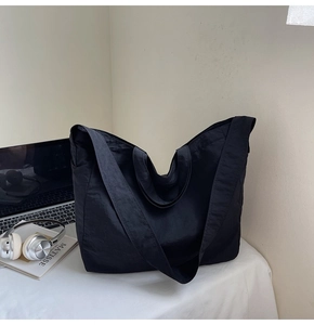 Détail du sac cabas noir minimaliste avec tissu en nylon texturé sur un bureau