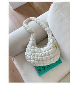 Detailansicht der cremefarbenen Stepptasche mit grünem Fashion-Label an der Seite