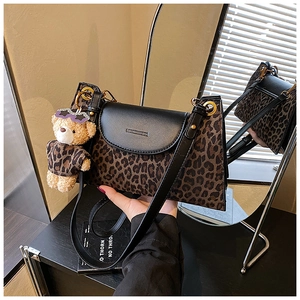 Détail d'un sac bandoulière à motif léopard avec rabat en cuir noir et breloque ourson