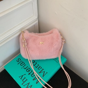 Détail de la texture en fausse fourrure rose et plaque logo dorée sur le sac bandoulière