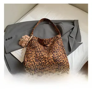 Detail shot of leopard print tote bag with brown bear plush charm and suit styling