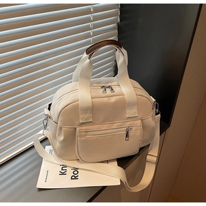Close-up of cream canvas tote bag showing brown leather handles and adjustable strap