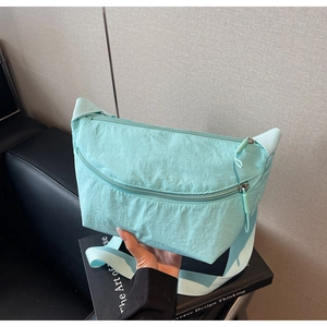 Detail of mint green nylon crescent bag showing crinkled texture and dual zippers