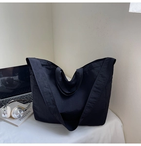 Vue détaillée du sac cabas en nylon noir montrant sa texture fine avec un ordinateur