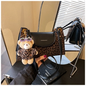 Détail d'un sac léopard avec rabat en cuir noir et charmant pendentif d'ours en peluche