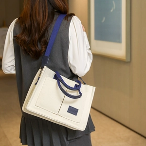 Détail d'un sac cabas en toile crème avec bandoulières bleues et doubles poches