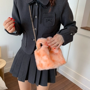 Detail of orange pink plush bucket bag with golden chain strap on a model