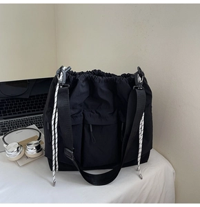 Detail of black waterproof nylon tote bag with utility pockets and drawstrings