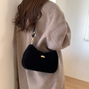 Détail du sac à bandoulière en fausse fourrure noire avec plaque dorée et lanière cuir