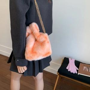 Detail of soft orange plush crossbody bag with elegant gold chain strap and fluffy texture