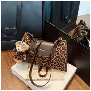 Gros plan du sac léopard avec garniture en cuir marron et pendentif ours en peluche