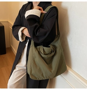 Detail of the large olive green nylon tote bag showing adjustable straps and spacious interior
