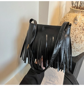 Detail der schwarzen Kunstleder-Beuteltasche mit langen Fransen und verstellbarem Gurt