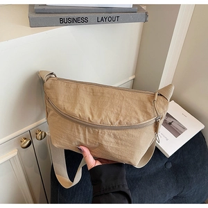 Detail of khaki nylon crescent bag with metal zippers and wide woven shoulder strap