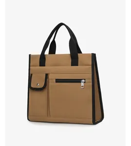 Detail of khaki canvas tote bag featuring reinforced black handles and front pocket with snap