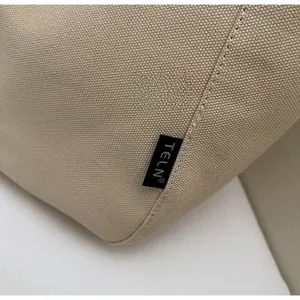 Macro shot of beige canvas tote bag showing woven texture and precise stitching detail