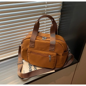 Detail of caramel nylon tote bag texture and side pocket design on metal surface