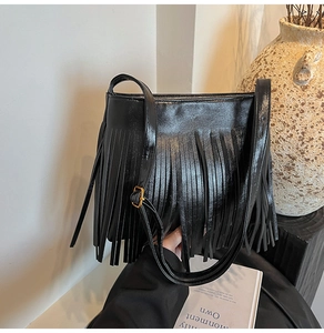 Detail der Vintage-Eimertasche aus schwarzem Wildleder mit langen Fransen und Goldbesatz