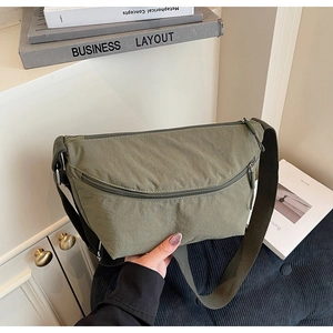Close-up of olive green nylon crescent bag showing wide strap and zip texture