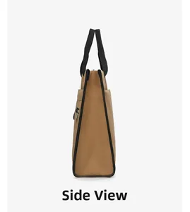 Side view of khaki canvas tote bag featuring black handles and a zippered side pocket